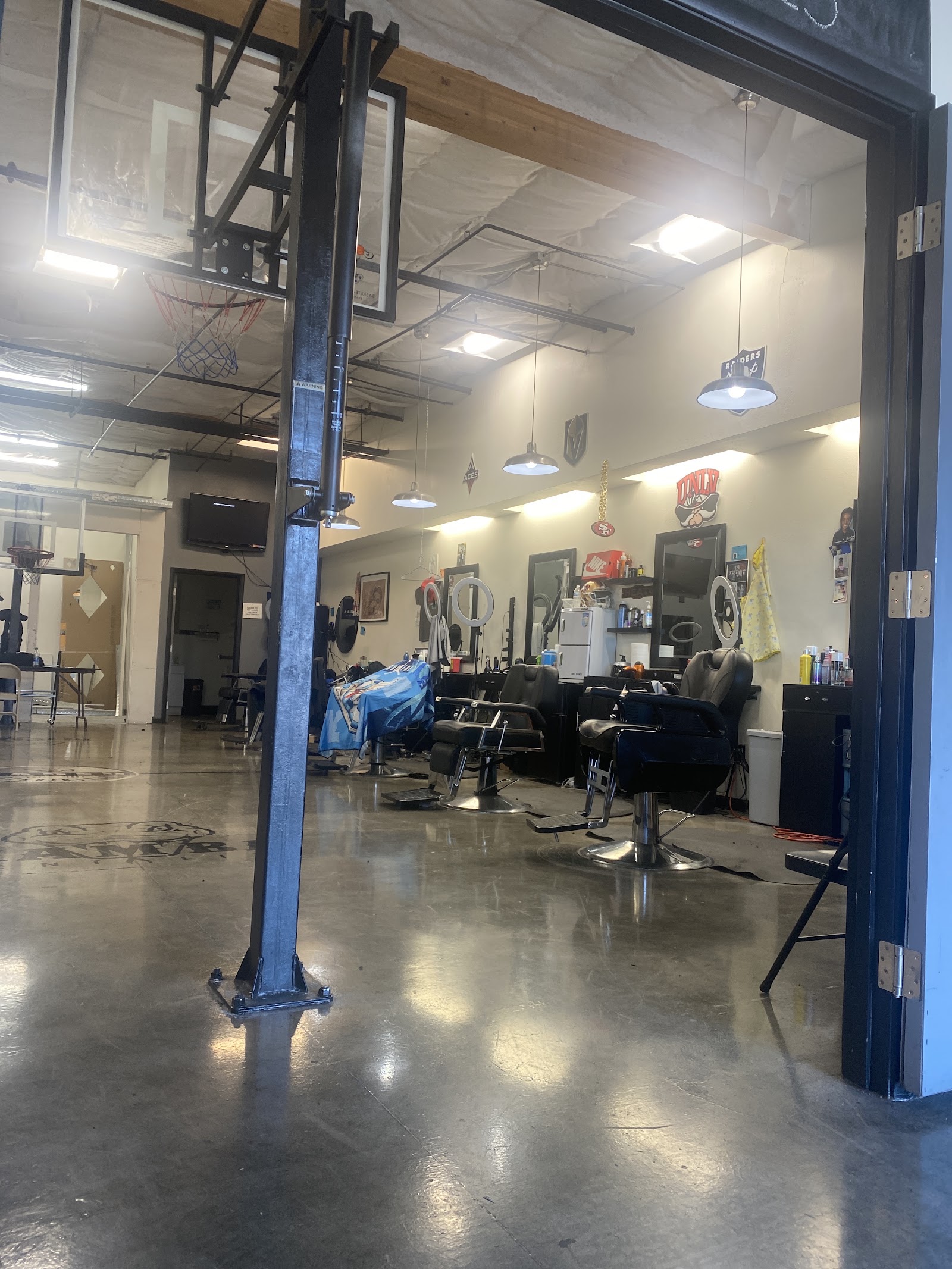 Interior of barbershop with barber chairs, mirrors and a basketball hoop in a spacious warehouse-style space